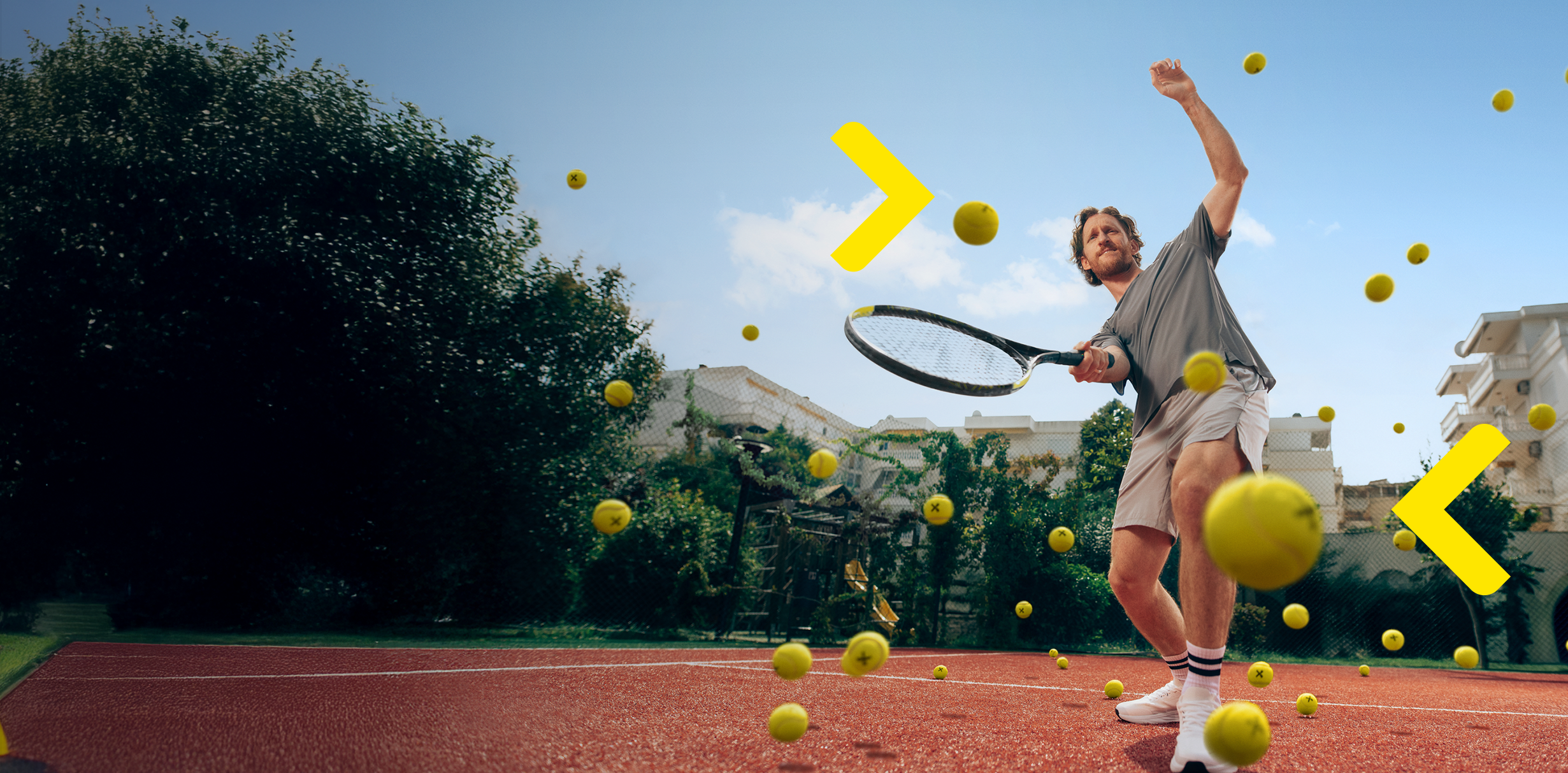 Férfi a teniszpályán sárga teniszlabdákat ütöget.